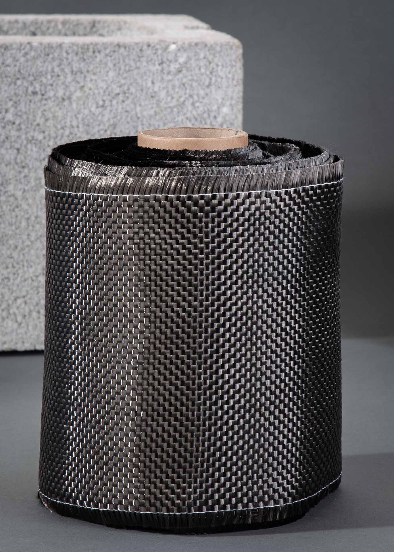 Image of Carbon Fiber Support's CFS 600- by the foot 600gsm 6″ Carbon Fiber Support Roll shown next to a cinder block.